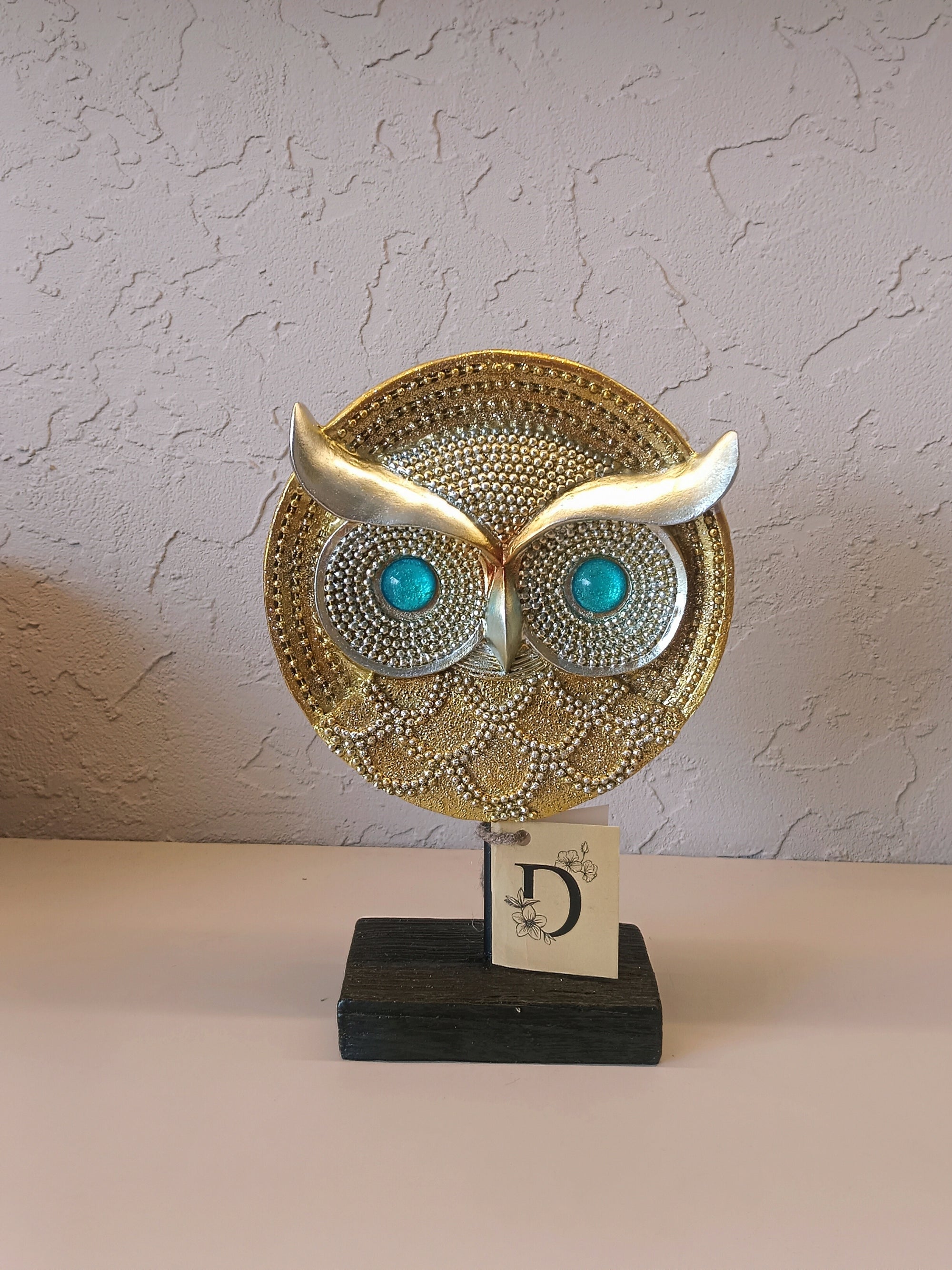 Artistic owl face sculpture with golden detailing, turquoise eyes