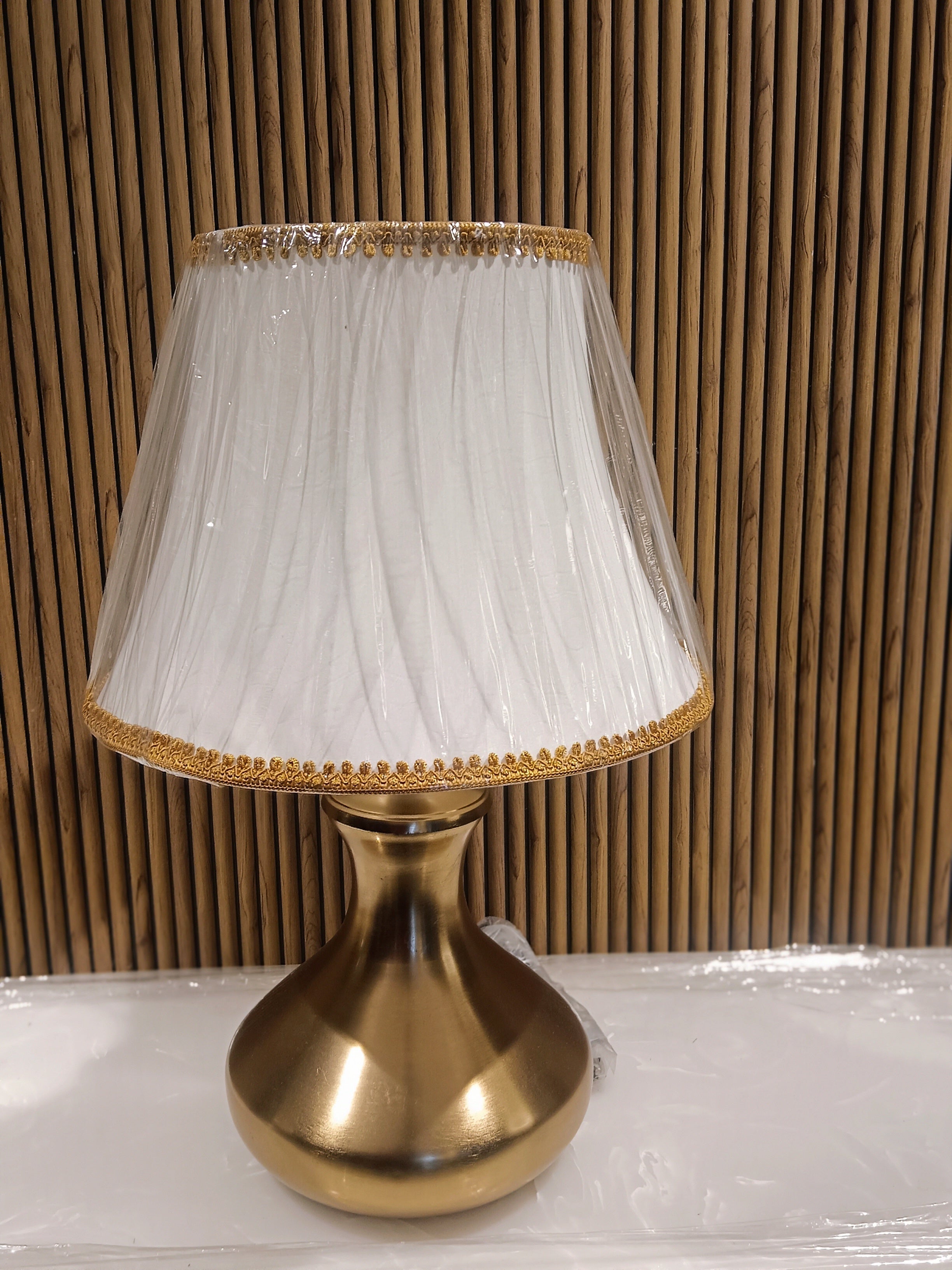 Elegant Table Lamp With A Golden Metallic Base And A White Fabric Lampshade Accented With Golden Lace Trim.