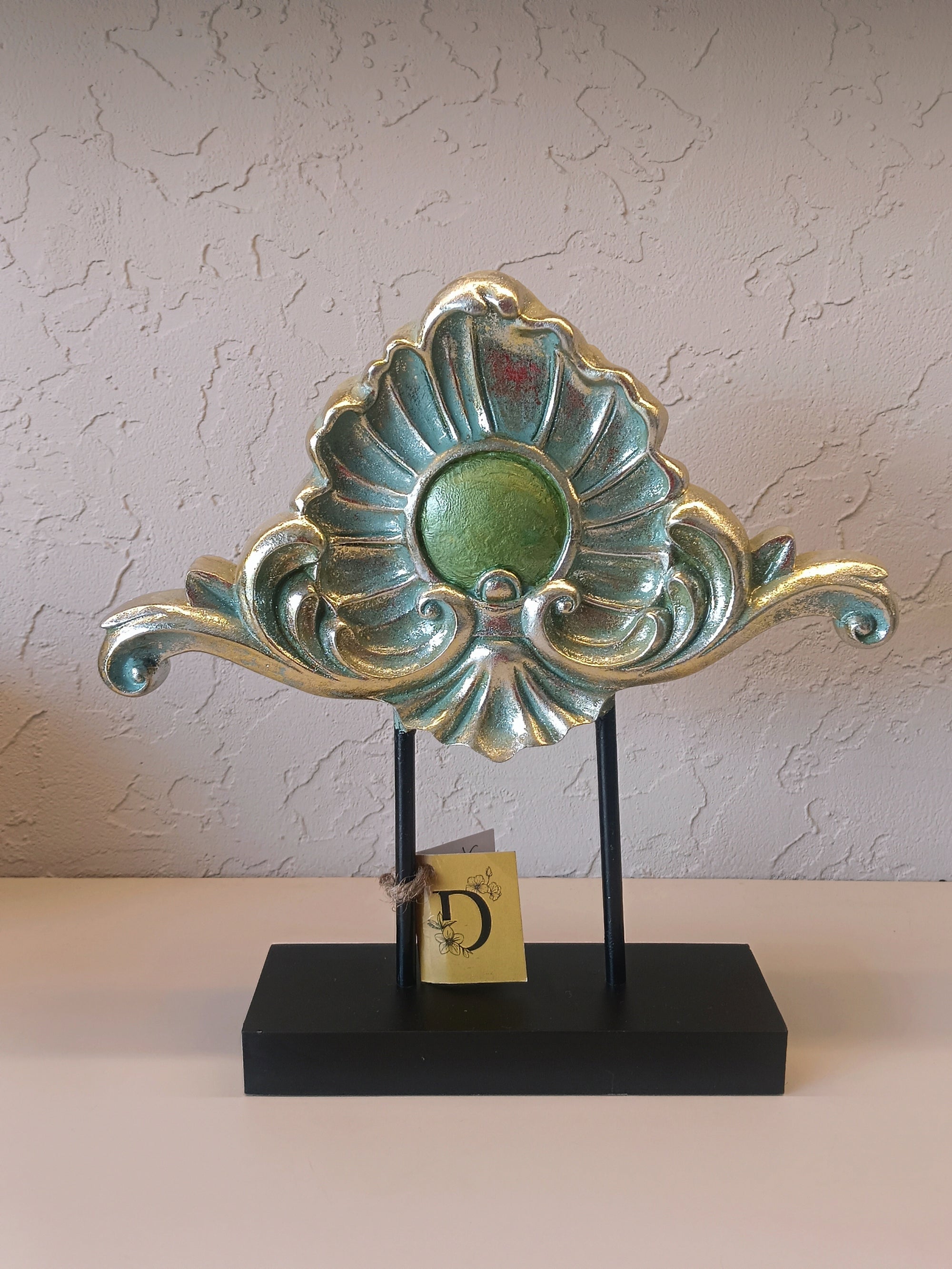A Decorative Tabletop Ornament With An Elegant Fan-Shaped Motif, Featuring Green And Gold Metallic Accents.