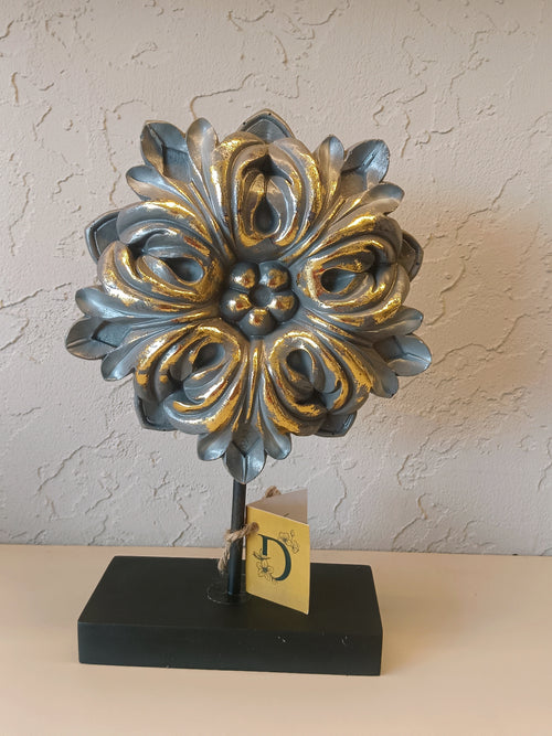A Decorative Tabletop Ornament Featuring An Ornate Floral-Inspired Design With A Metallic Silver And Gold Finish.