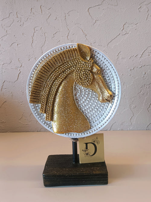 A Decorative Tabletop Ornament Featuring A Stylized Horse Head In Glittering Gold