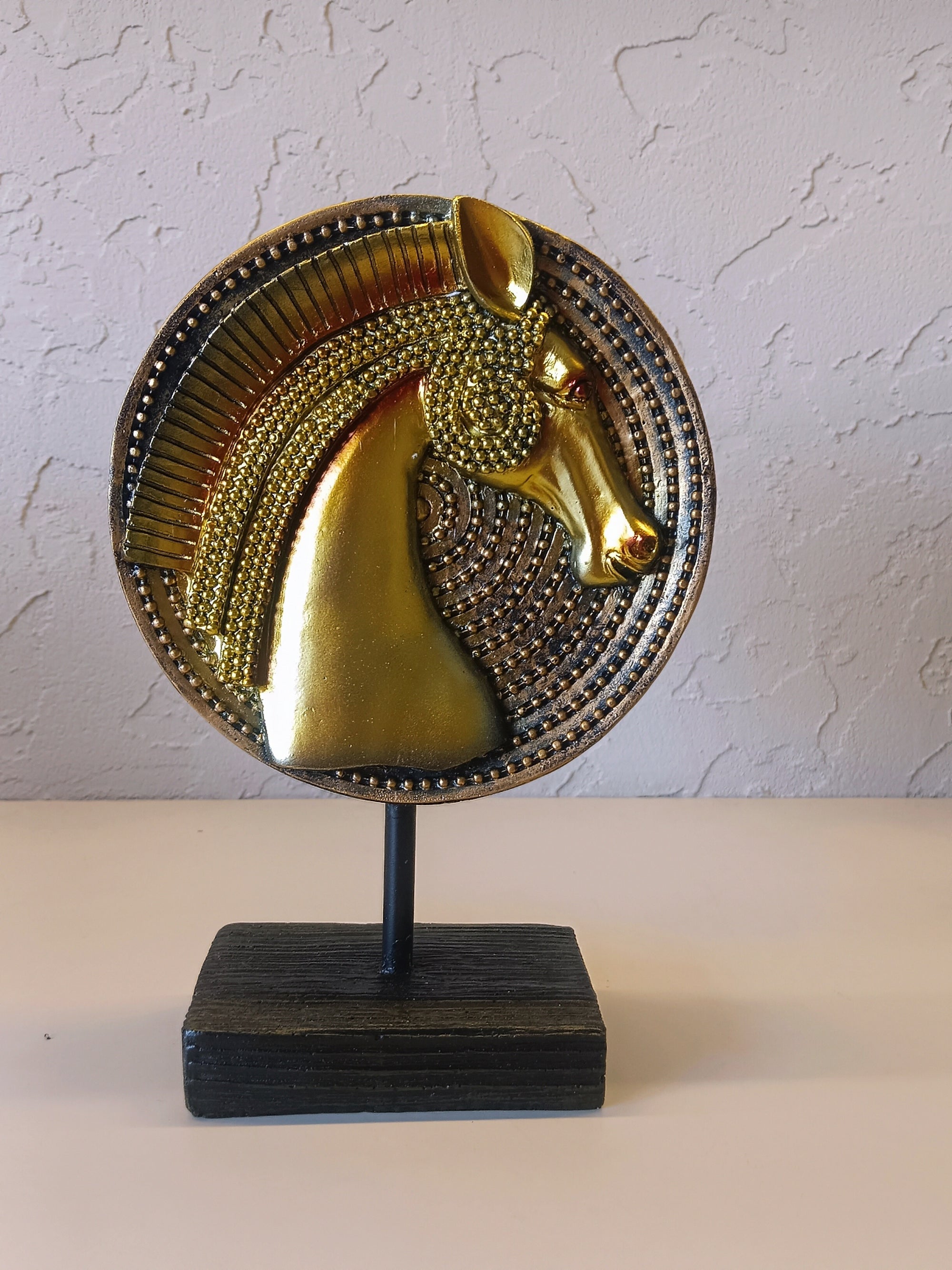 Golden Horse Head Sculpture On A Circular Textured Base, Mounted On A Sturdy Wooden Stand. A Bold And Elegant