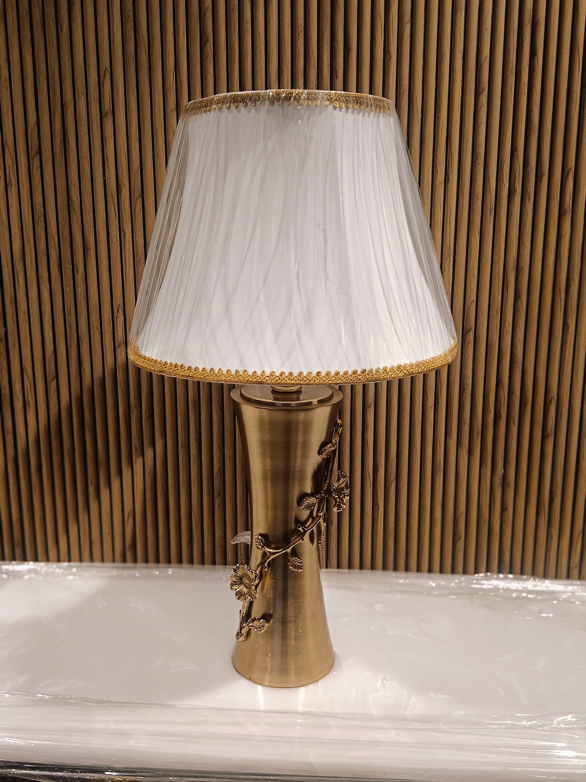 Elegant Table Lamp With A Golden Metallic Base Featuring Intricate Floral Dine Detailing