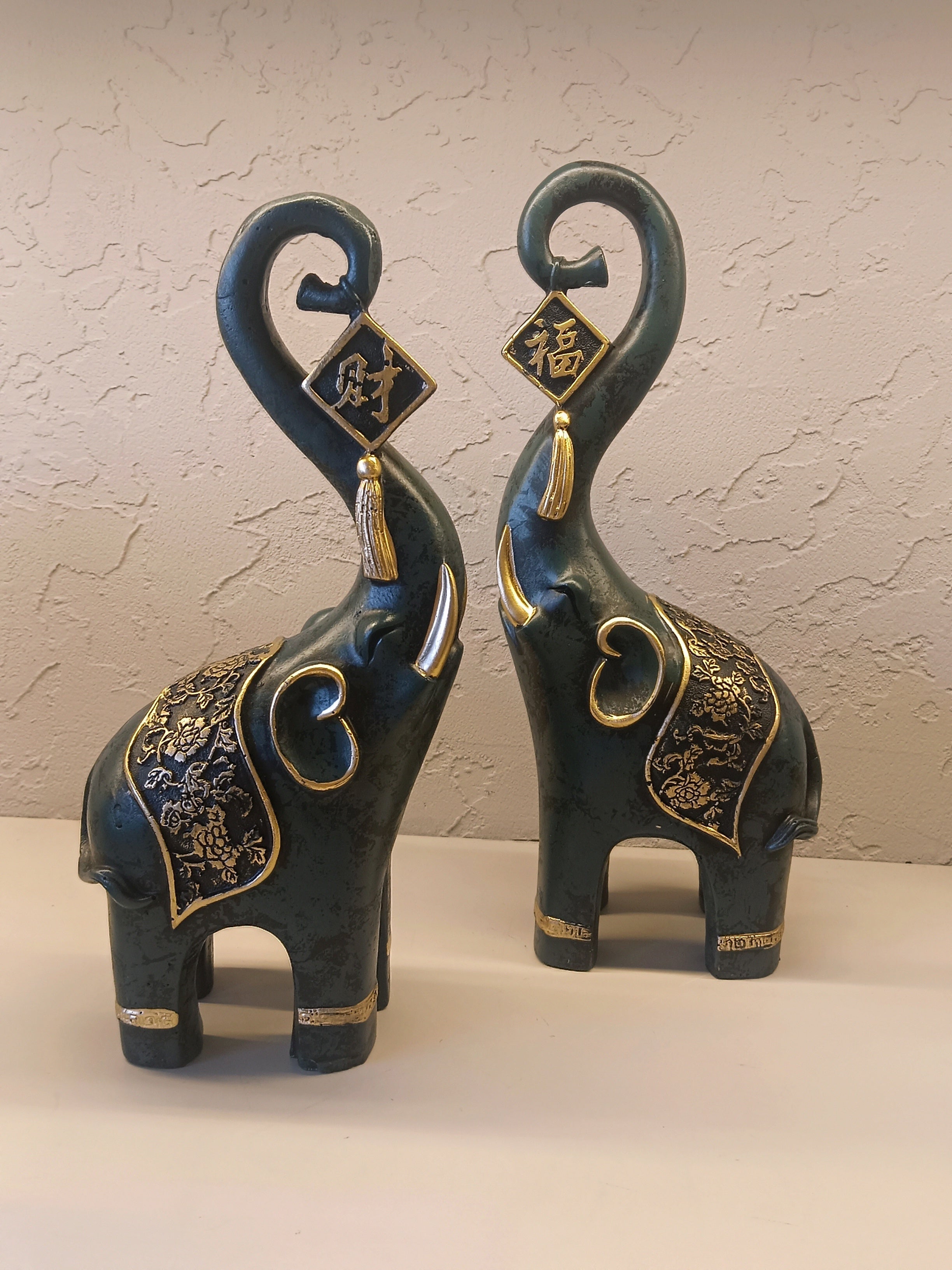 A Pair Of Intricately Crafted Decorative Elephant Figurines With Trunks Raised High, Symbolizing Prosperity