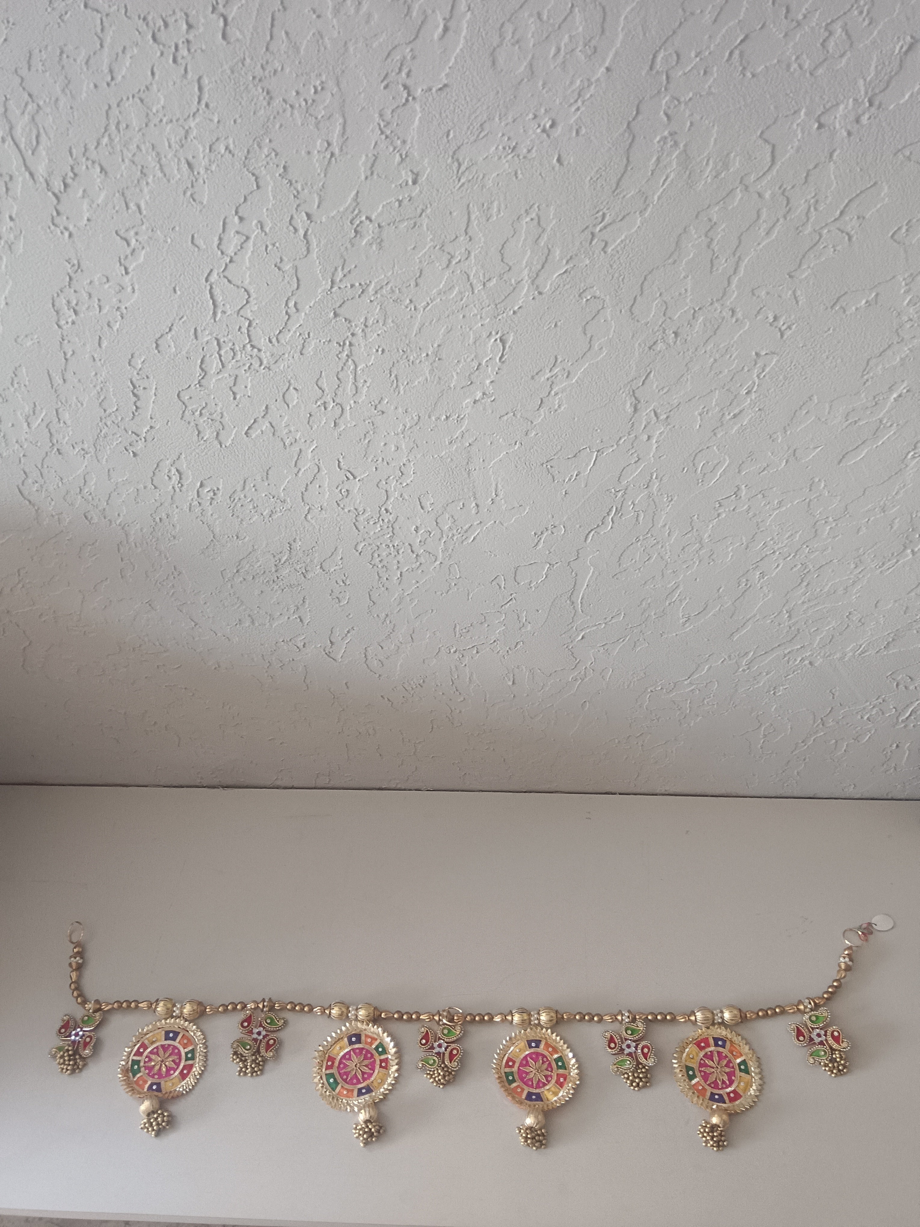 A Handcrafted Ornamental Toran Featuring Intricate Circular And Paisley Motifs In Gold With Vibrant Enamel Detailing