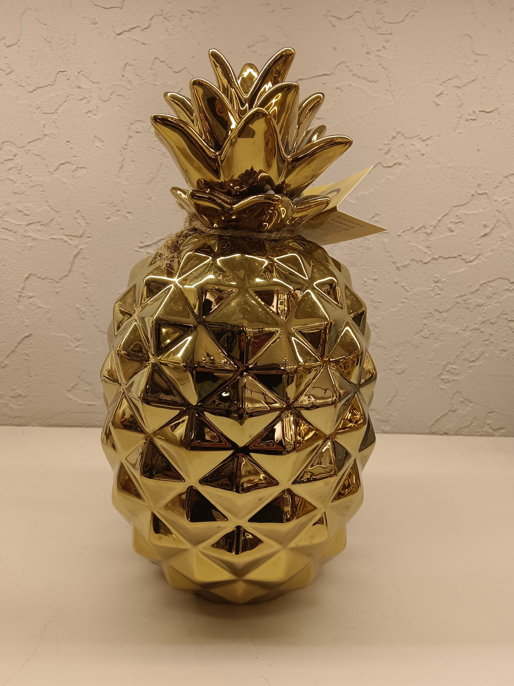 Two shiny, gold-finished ceramic pineapple figurines, each with a textured geometric design