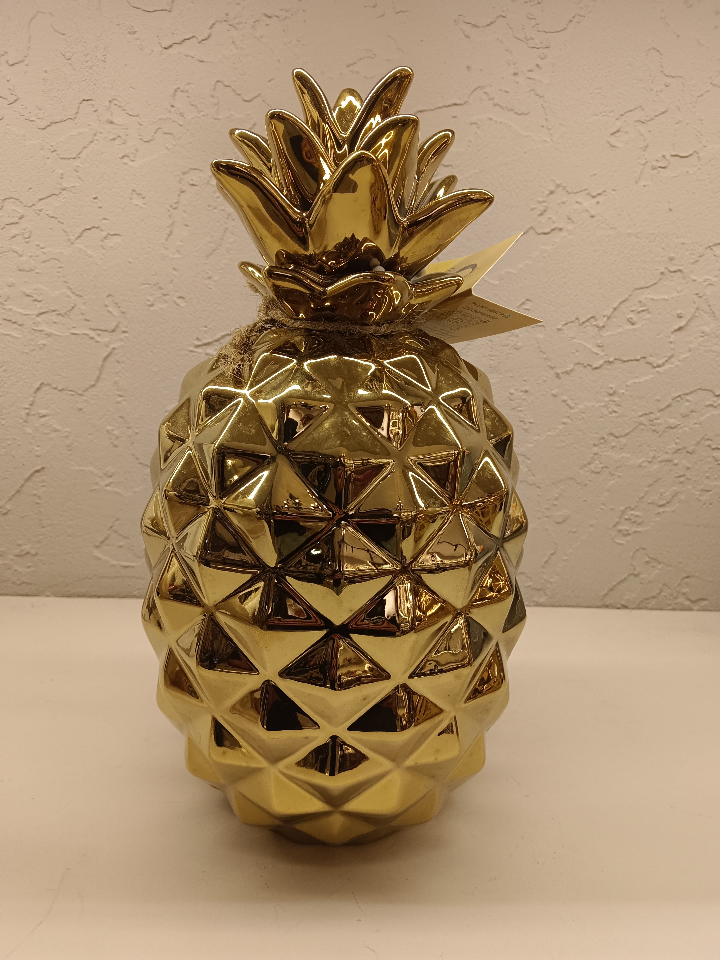 Two shiny, gold-finished ceramic pineapple figurines, each with a textured geometric design