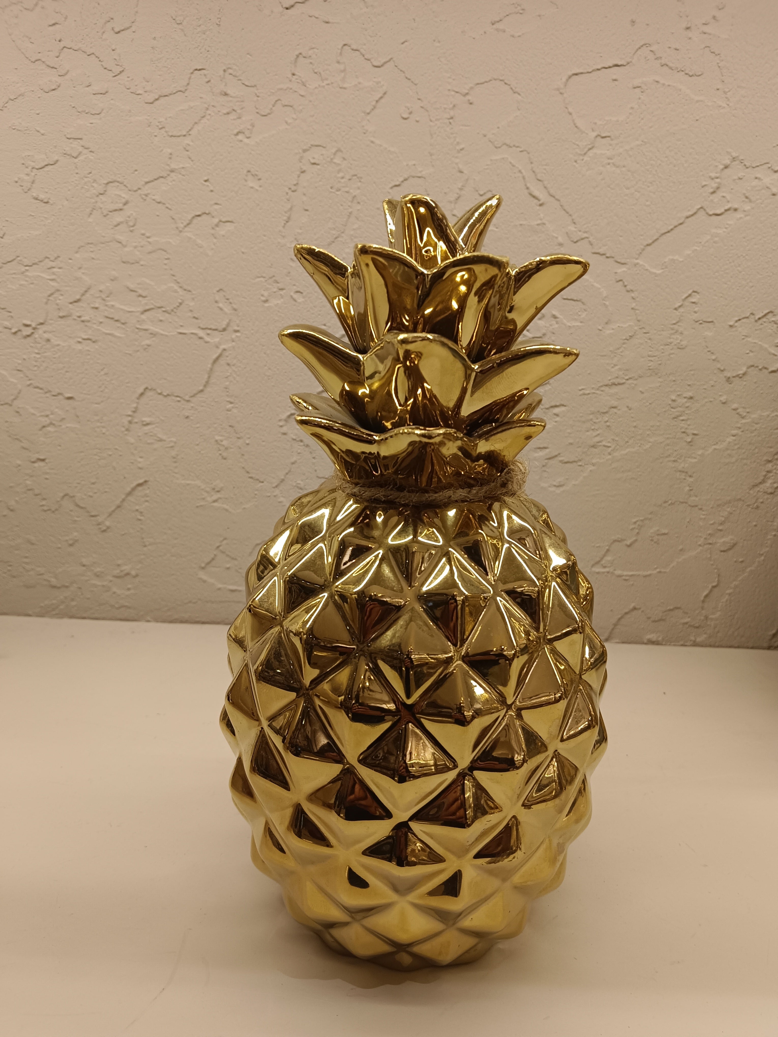Two shiny, gold-finished ceramic pineapple figurines, each with a textured geometric design