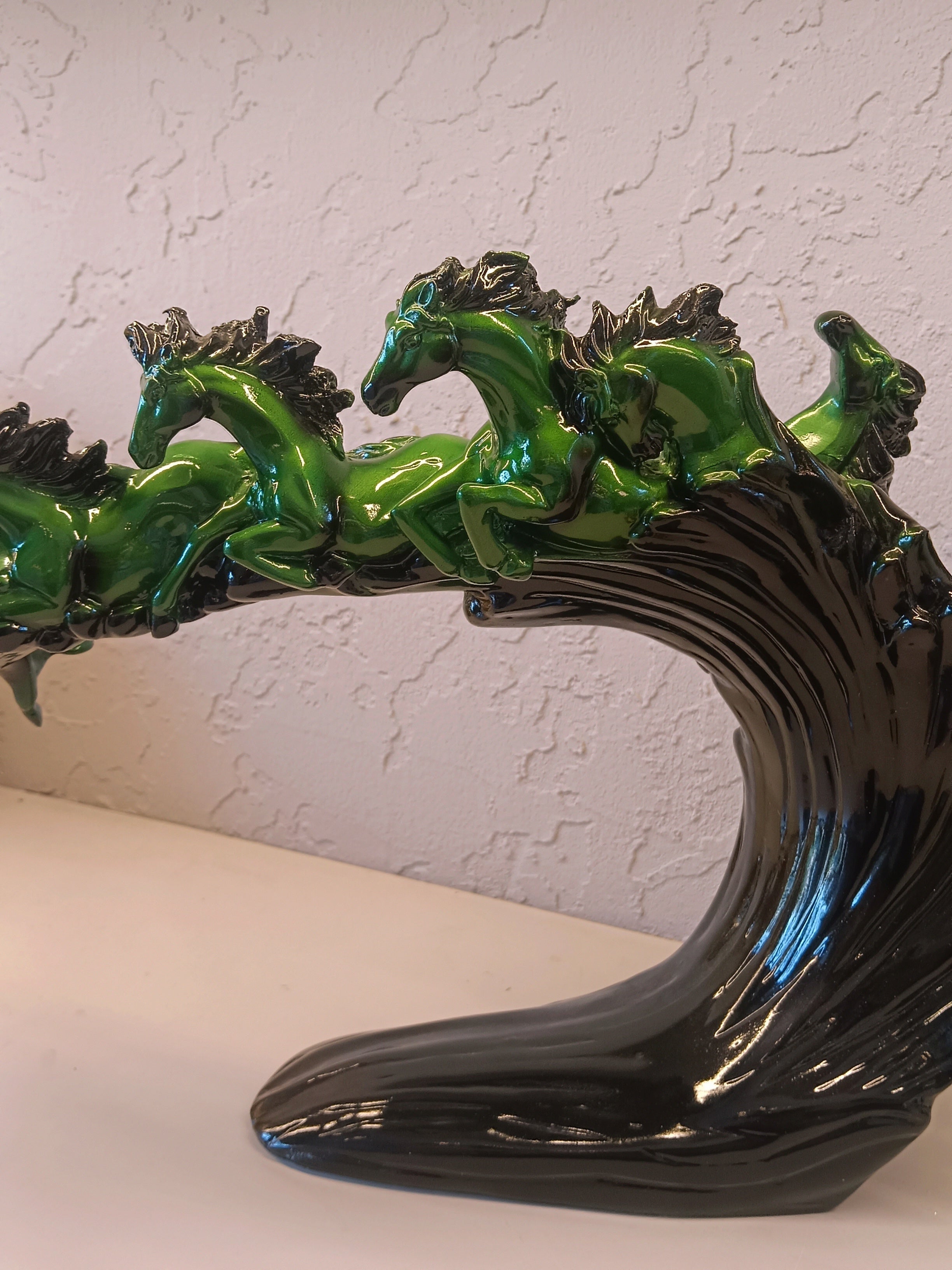 Dynamic and artistic sculpture of running horses, designed with a glossy green and black