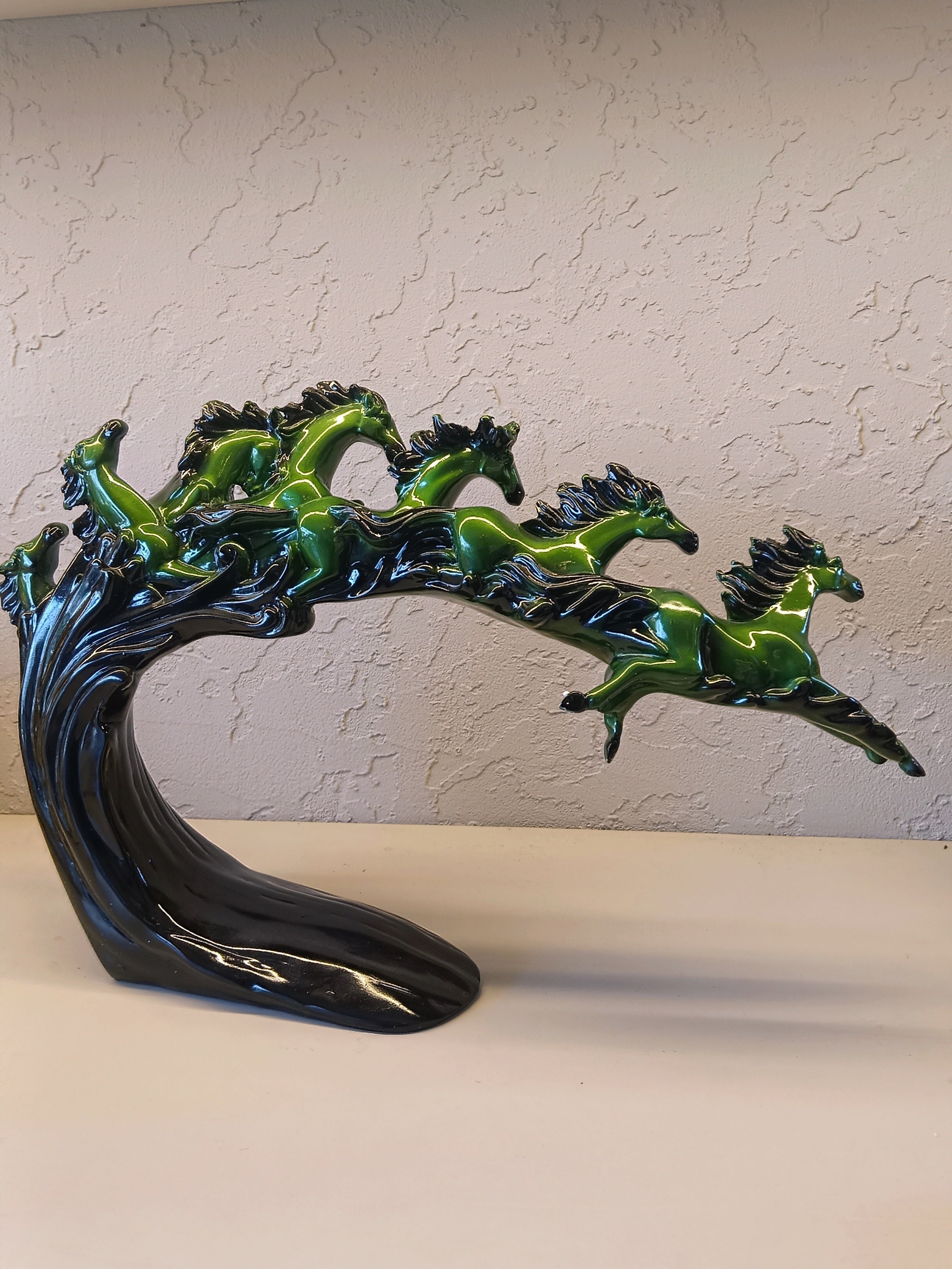 Dynamic and artistic sculpture of running horses, designed with a glossy green and black