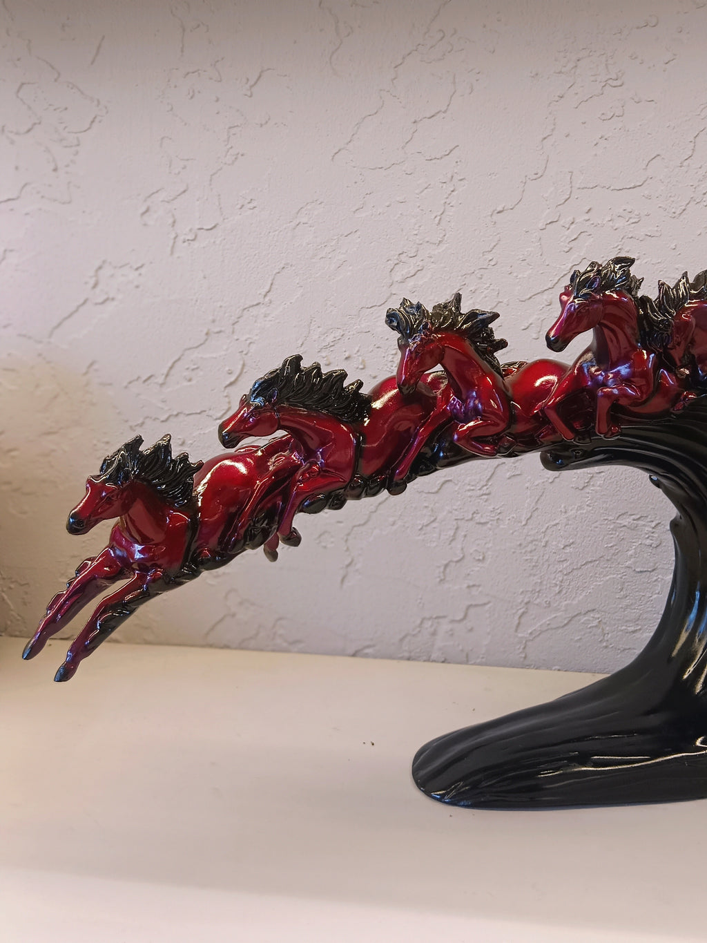 Dynamic and artistic sculpture of running horses, designed with a glossy maroon and black