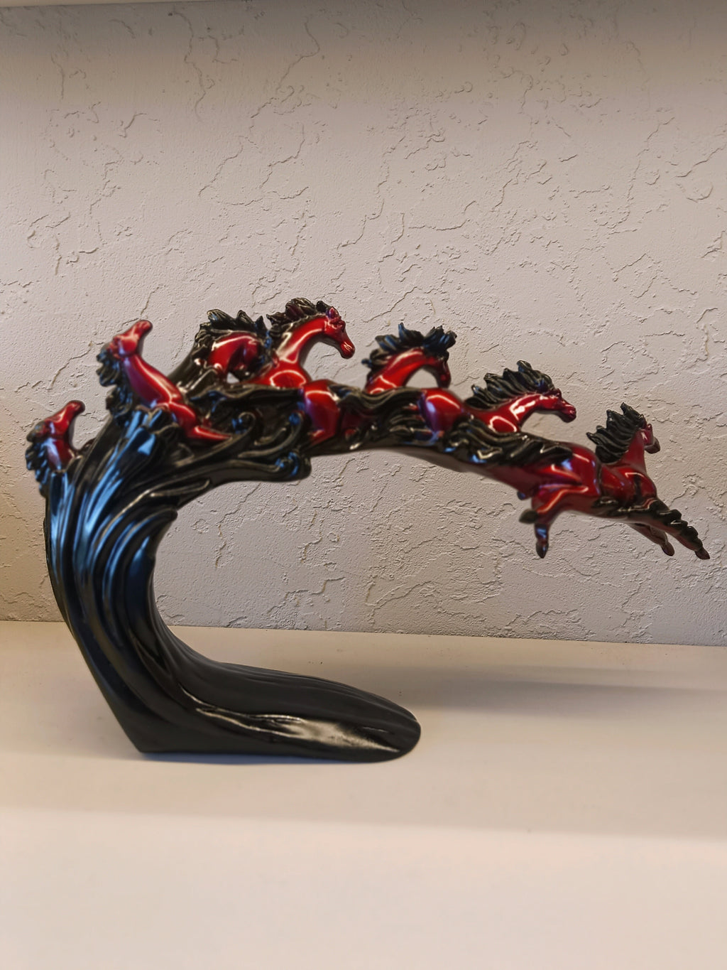 Dynamic and artistic sculpture of running horses, designed with a glossy maroon and black